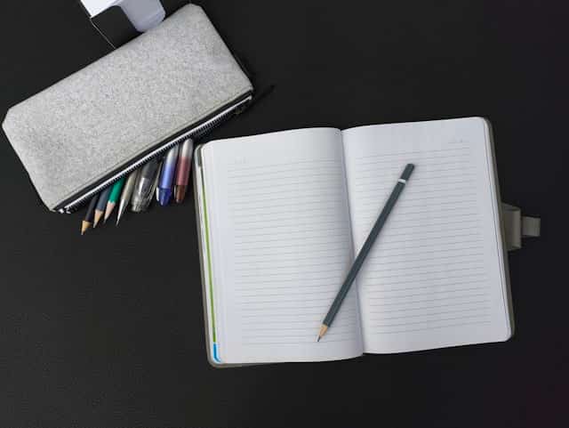 Open notebook and pencils on a dark desk