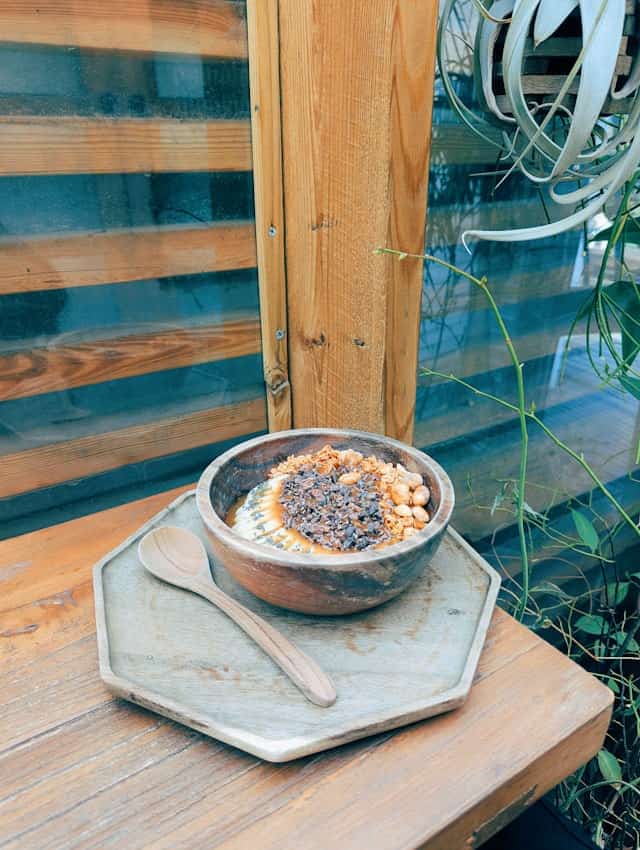 Wooden bowl of fruit and granola on a table