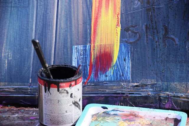 Paint can and brush beside a painted surface