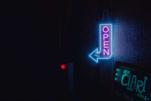 Neon OPEN sign with arrow in a dark shopfront
