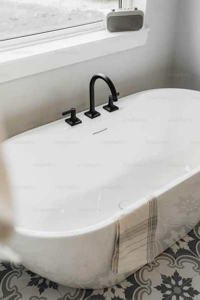 White bathtub beside patterned wall tiles