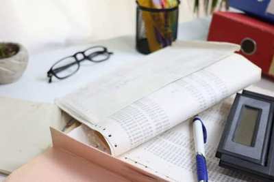 Open accounting ledger, calculator, and stationery on an office desk