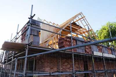 House under construction with scaffolding and exposed brickwork