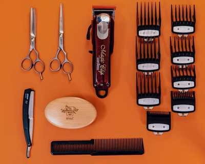 Hairdressing scissors, combs, and clippers arranged on orange